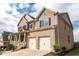 A low angle view of a two-story brick home with a front porch and attached two-car garage in a suburban neighborhood at 570 Eldridge Dr, Suwanee, GA 30024