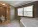 Bright bathroom with a soaking tub, tiled shower, and a large window at 619 Stoney Creek Rd, Woodstock, GA 30188