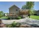 Home's back exterior with an elevated deck, a lower-level patio, and landscaped backyard with green grass at 619 Stoney Creek Rd, Woodstock, GA 30188