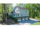 View of the home's rear exterior highlighting the 3-car garage with a sloped driveway and mature trees at 619 Stoney Creek Rd, Woodstock, GA 30188