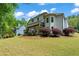 Large grassy backyard with an elevated deck, a covered patio, mature trees, and beautiful landscaping at 1749 Patriots Nw Way, Kennesaw, GA 30152