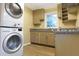 A compact kitchen features a stackable washer/dryer, granite countertops, and modern appliances at 1083 Grace Dr, Forest Park, GA 30297
