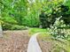 Serene backyard featuring a walking path, shed, lush greenery, and blooming shrubs at 2870 Willow Wisp Way, Cumming, GA 30040