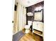 Full bathroom featuring a shower with white and beige striped curtain, wooden floors, dark floral wallpaper and white sink at 2870 Willow Wisp Way, Cumming, GA 30040
