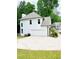 Side view of a white home featuring an attached garage and lush green surroundings on a sunny day at 2870 Willow Wisp Way, Cumming, GA 30040