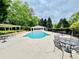 Community pool with tables and chairs surrounded by lush green trees, a cabana and a pergola at 2870 Willow Wisp Way, Cumming, GA 30040