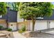Charming townhome featuring a white door, brick accents, and mature trees, creating a welcoming curb appeal at 5250 Chemin De Vie, Atlanta, GA 30342
