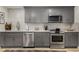 Well-lit kitchen featuring stainless steel appliances, gray cabinets, and wood floors at 5250 Chemin De Vie, Atlanta, GA 30342
