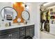 Bathroom with dual vanity, round mirrors, wood paneling, and a walk-in closet at 371 Northaven Ave, Suwanee, GA 30024