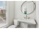 Chic powder room features a pedestal sink with gold fixtures and natural light from a window at 427 Burton Dr, Alpharetta, GA 30009