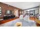 Open-concept living space features a brick accent wall, hardwood floors, and a clear view to the kitchen and dining area at 201 W Ponce De Leon Ave # 402, Decatur, GA 30030