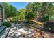 Backyard with a stone patio, landscaping, and an in-ground fire pit at 4035 Regal Oaks Dr, Suwanee, GA 30024