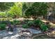 Landscaped backyard featuring a fire pit, trees, bushes, and a chair at 4035 Regal Oaks Dr, Suwanee, GA 30024