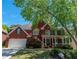 Charming red brick home with a welcoming front porch and lush landscaping at 4035 Regal Oaks Dr, Suwanee, GA 30024