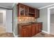 Charming wet bar boasts granite counters, tile backsplash, sink, wine rack, and glass-front cabinets at 4035 Regal Oaks Dr, Suwanee, GA 30024