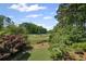 Lush backyard view showcasing mature trees, a manicured lawn, and golf course in the distance at 6725 Polo Dr, Cumming, GA 30040