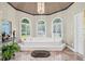 Bright bathroom with soaking tub, chandelier, arched windows and marble tile floors at 6725 Polo Dr, Cumming, GA 30040