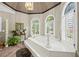 Bright bathroom with soaking tub, chandelier, arched windows and stained glass accents at 6725 Polo Dr, Cumming, GA 30040
