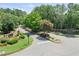 Landscaped community entrance with stone signage surrounded by lush greenery and a well-maintained roadway at 6725 Polo Dr, Cumming, GA 30040