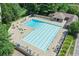 Large rectangular community pool with lounge chairs, umbrellas, and a covered seating area surrounded by landscaping at 6725 Polo Dr, Cumming, GA 30040