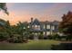 Beautiful home exterior with a manicured lawn, mature trees, and architectural details at sunset at 6725 Polo Dr, Cumming, GA 30040