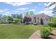 Charming home featuring a large front lawn with mature landscaping, trees, and architectural roofline at 6725 Polo Dr, Cumming, GA 30040
