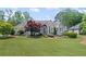 Charming home featuring a large front lawn with mature landscaping, trees, and architectural roofline at 6725 Polo Dr, Cumming, GA 30040