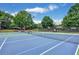 Well-maintained community tennis court with lighting, seating, and mature trees, offering a great recreational space at 6725 Polo Dr, Cumming, GA 30040