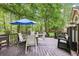 Inviting back deck surrounded by lush trees and an outdoor dining area with seating for eight at 989 Pinfeather Ct, Lawrenceville, GA 30043