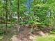 Backyard view through the trees, with lawn, mature trees, landscaping, and a partial view of the rear of the house at 989 Pinfeather Ct, Lawrenceville, GA 30043