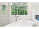 Bright bathroom featuring a soaking tub with white tile walls at 989 Pinfeather Ct, Lawrenceville, GA 30043
