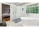 Elegant bathroom with a freestanding tub, separate glass shower, and access to the main bedroom at 989 Pinfeather Ct, Lawrenceville, GA 30043