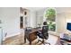 Stylish home office featuring hardwood floors, a classic desk, and a large window providing natural light and outdoor views at 989 Pinfeather Ct, Lawrenceville, GA 30043