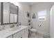 Bright bathroom features a white single sink vanity, framed mirror, toilet, and window at 146 Citrine Way, Acworth, GA 30101
