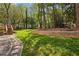 Sprawling backyard featuring a stone retaining wall, walkway, and lush greenery, ideal for outdoor activities at 125 Roswell Farms Ln, Roswell, GA 30075