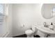Bright powder room featuring a pedestal sink, round mirror, and window with blinds at 813 Ambient Sw Way, Atlanta, GA 30331