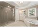 Bathroom with large shower, white cabinets, soaking tub, and a large window at 891 Berryman Pl, Lawrenceville, GA 30045