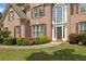 Close-up of a brick home with a prominent front door, enhanced by manicured hedges and vibrant flowerbeds at 891 Berryman Pl, Lawrenceville, GA 30045