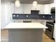 Kitchen features stainless steel appliances, blue herringbone backsplash, island, and white cabinets at 1384 Allegheny Sw St, Atlanta, GA 30310