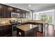 Eat-in kitchen with stainless appliances, dark wood cabinetry, granite countertops, and view of the bright sunroom at 6170 Weddington Dr, Cumming, GA 30040