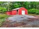 Exterior view of a large red barn with a roll-up garage door and a gravel driveway at 65 Maude White Rd, Kingston, GA 30145