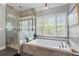 Bright bathroom boasts a large soaking tub, glass-enclosed shower and stylish chandelier at 65 Maude White Rd, Kingston, GA 30145