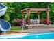Poolside dining area with pergola surrounded by lush greenery and colorful flowers at 65 Maude White Rd, Kingston, GA 30145