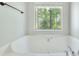 Soaking tub beneath a window with a view of the green trees at 2919 Camplay Dr, Suwanee, GA 30024