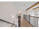 Upstairs hallway with wood flooring, wooden beams, iron railings, and light fixture at 3390 Hillshire Dr, Cumming, GA 30028