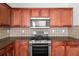 Well-lit kitchen featuring wood cabinets, stainless steel appliances, and stylish tiled backsplash at 145 Redsage Rdg, Atlanta, GA 30349