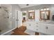 Bright bathroom with white cabinets, dual sinks, wood-look tile floor, and large glass shower at 4540 Saddle Se Ct, Smyrna, GA 30082
