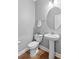 This powder room has a pedestal sink, round mirror and wood-look floor at 123 Academy Ln, Canton, GA 30114