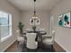 Bright dining room features a modern chandelier, neutral walls, and a circular dining table set for five at 436 Vermeer Ct, Locust Grove, GA 30248