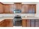 A close-up of the kitchen area featuring wood cabinets, granite countertops, and stainless steel appliances at 436 Vermeer Ct, Locust Grove, GA 30248